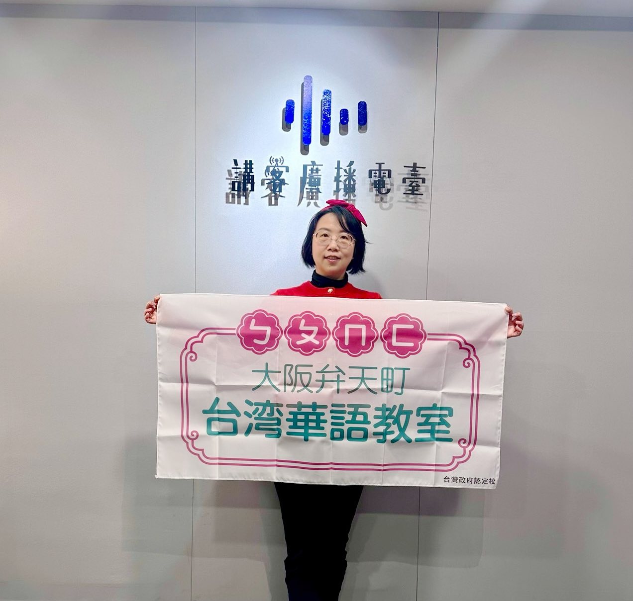 陳洳豔校長於講客廣播電台手持「大阪弁天町台灣華語教室」布條留影