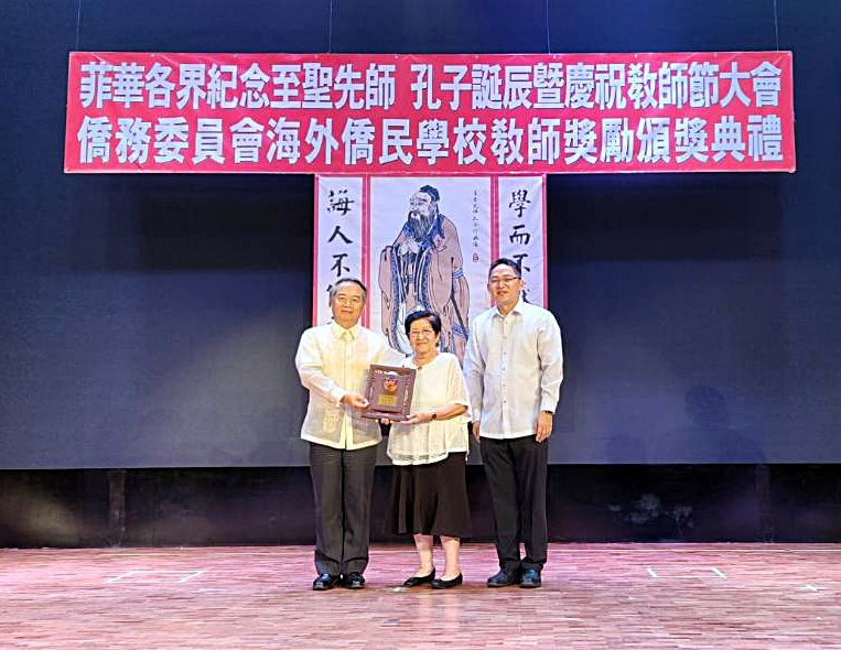 大使周民淦〈左〉頒贈獎座給執教50年的資深優良教師嘉南中學副校長許麗玲(中)，菲華文教服務中心主任莊博智同臺見證
