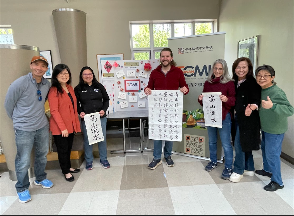 TCML文化主任李珠瑛與學生們在TCML展示桌前，與其各種作品合影 